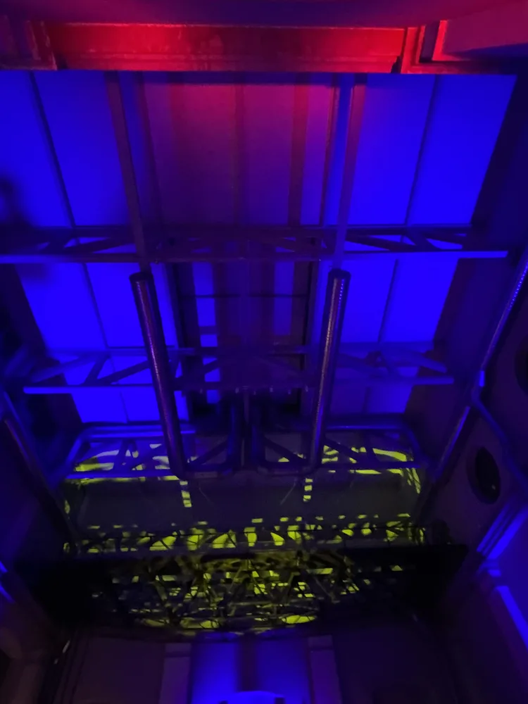 Soffitto della Ex Centrale ENEL — strutture industriali in acciaio rivelate da un lavaggio di luce blu con accenti rossi, composizione illuminotecnica SUONO E LUCE