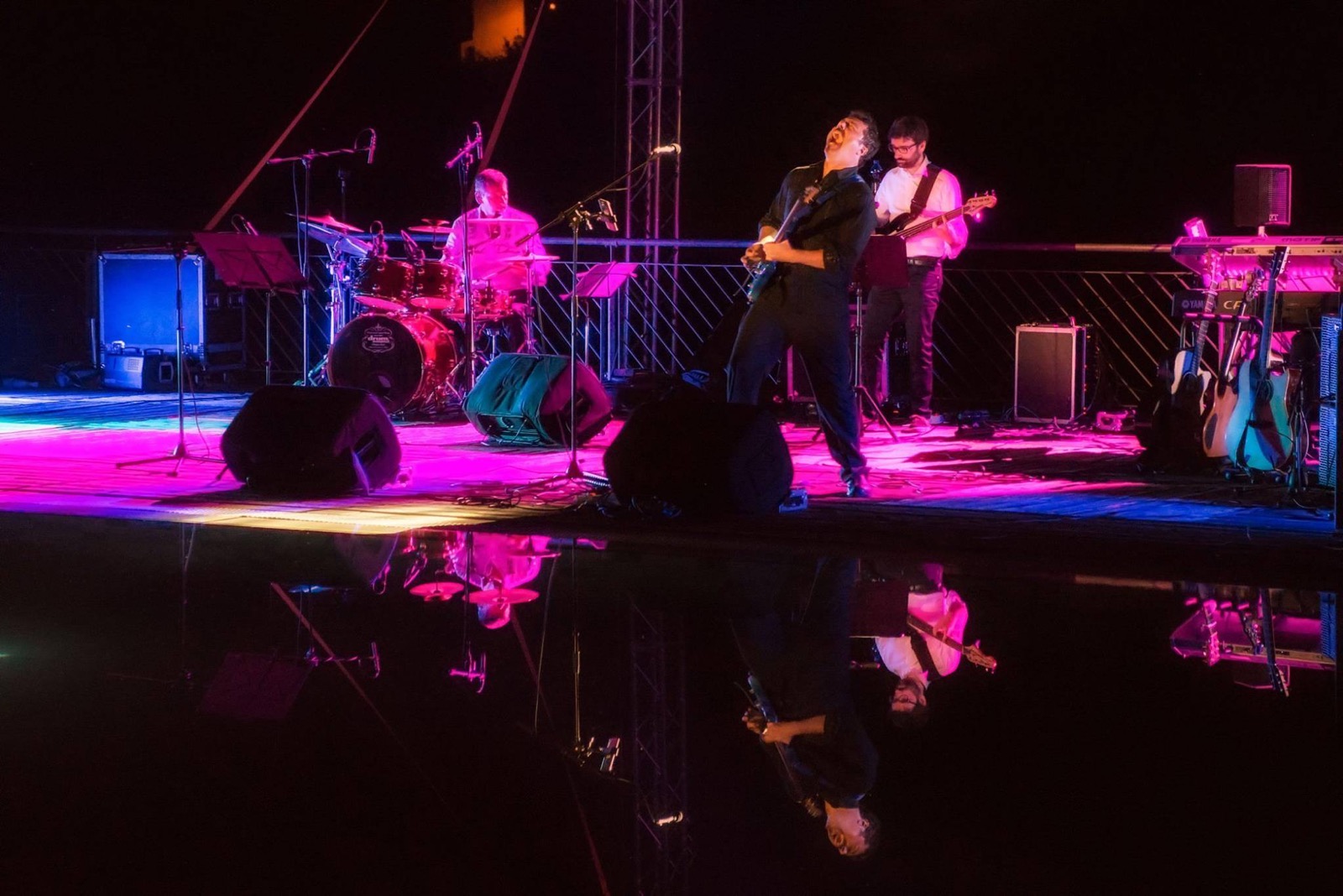 Gabor Lesko alla chitarra, riflesso viola sull'acqua del Ticino — light design per concerto jazz all'aperto, Note sull'Acqua Pavia 2018, SUONO E LUCE