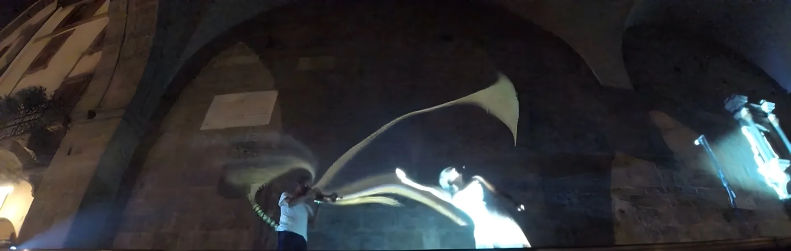 Trombettista suona sotto le volte a crociera del Palazzo della Ragione in Piazza Vecchia — scia luminosa proiettata dall'interazione tra suono e immagine, Danza Liquida Bergamo Alta, SUONO E LUCE