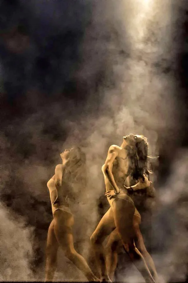 Danzatrici in controluce immerse nel fumo scenico con fascio di luce dall'alto — coreografia di Giancarlo Poliseno, light design SUONO E LUCE