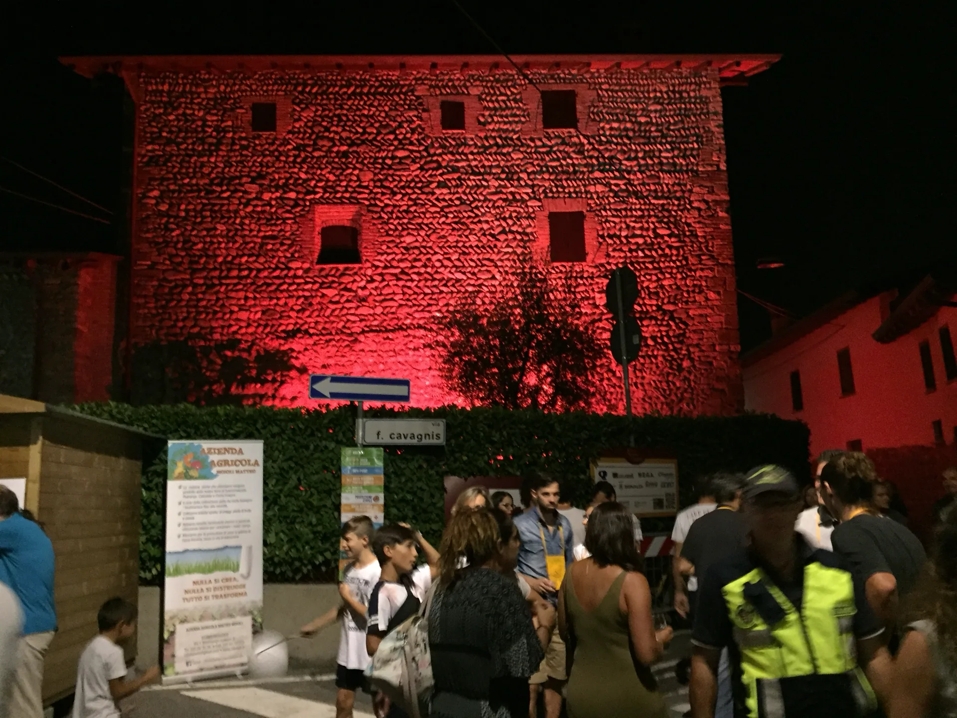 Facciata medievale in pietra illuminata di rosso con pubblico della Festa del Moscato di Scanzo — illuminazione architettonica SUONO E LUCE
