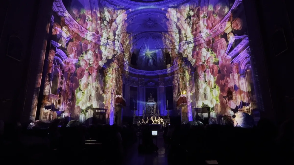 Proiezioni di fiori rosa e viola avvolgono l'intera navata di una chiesa — Luccicanti, spettacolo immersivo SUONO E LUCE
