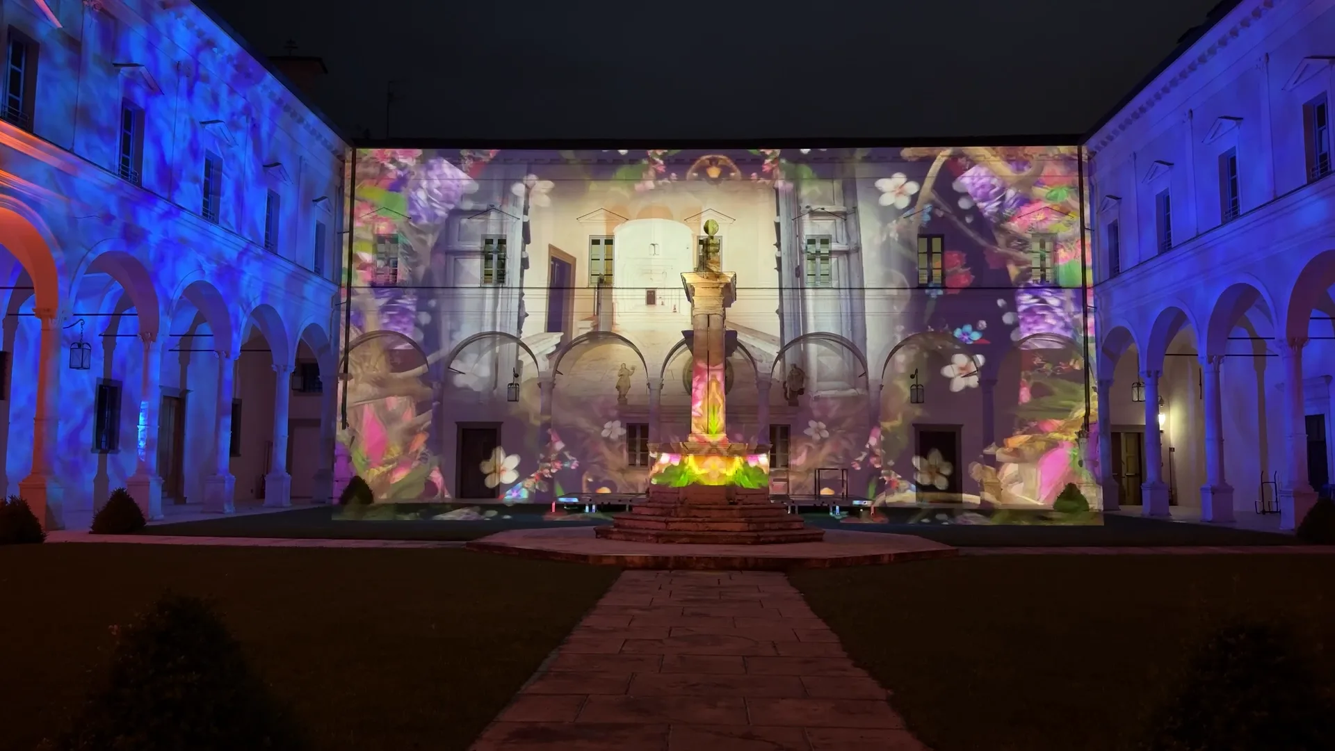 Fiori blu e viola con architettura del chiostro proiettati sulla facciata — light design e proiezioni su facciate per il patrimonio culturale, Abbazia di San Paolo d'Argon, SUONO E LUCE